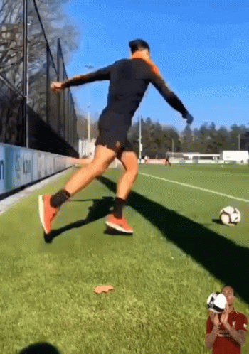 A Soccer Player Is Jumping In The Air To Kick A Ball GIF