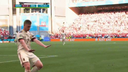 A Soccer Player Is Kicking A Ball On A Field With A Just Eat Banner In The Background GIF
