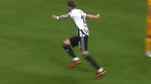 a soccer player is kneeling down on the field with his arms in the air .