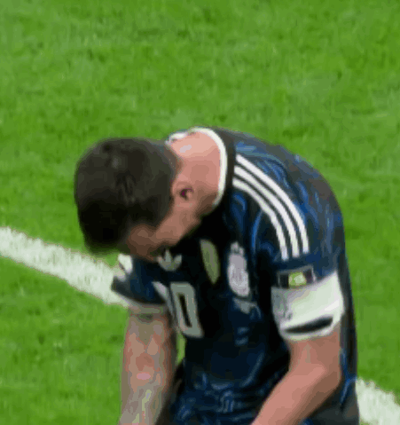 A Soccer Player Is Kneeling Down On The Field With His Head Down . GIF