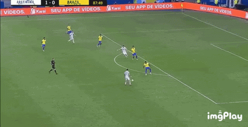 A Soccer Player Is Kneeling On The Field While Another Player Kicks The Ball . GIF
