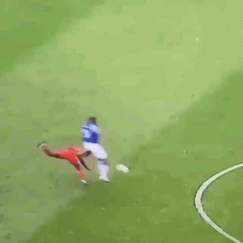 A Soccer Player Is Kneeling On The Field While Another Player Stands Behind Him . GIF