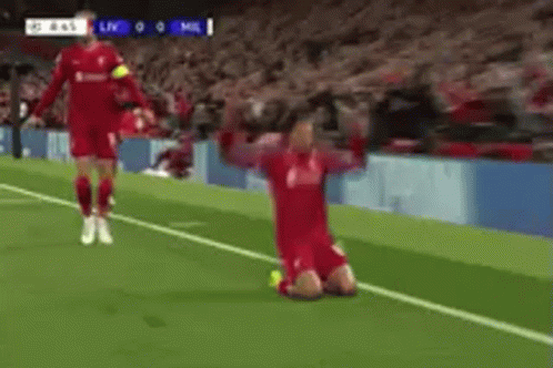A Soccer Player Is Kneeling On The Field With His Arms Outstretched While Another Player Runs Towards Him . GIF