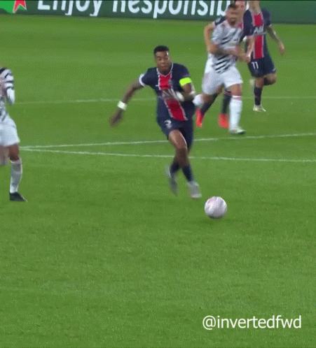 A Soccer Player Is Laying On The Ground While Another Player Is Jumping In The Air GIF
