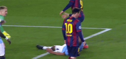 A Soccer Player Is Laying On The Ground While Another Player Tries To Help Him . GIF