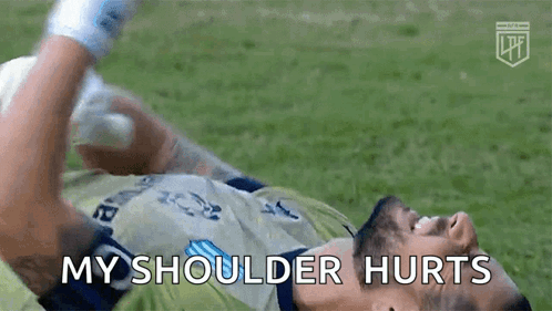 a soccer player is laying on the ground with his shoulder hurting