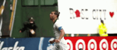 A Soccer Player Is Running In Front Of A Rose City Sign GIF