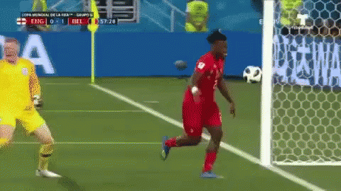 A Soccer Player Is Running Towards The Goal While A Goalie Stands Behind Him GIF