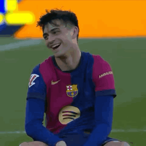a soccer player is sitting on the field laughing and smiling .