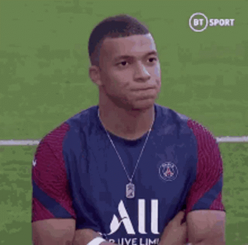 A Soccer Player Is Sitting On The Field With His Arms Crossed And Looking At The Camera . GIF