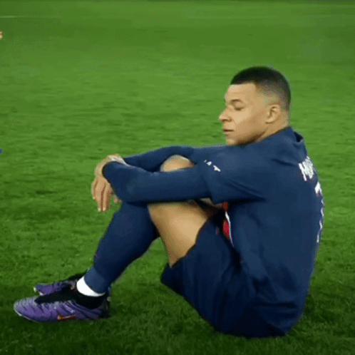 A Soccer Player Is Sitting On The Grass Wearing Purple Nike Shoes GIF