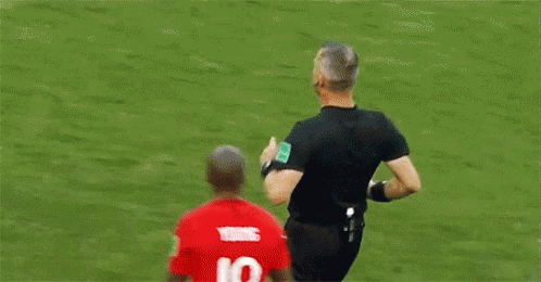 A Soccer Player Is Talking To A Referee On A Field . GIF