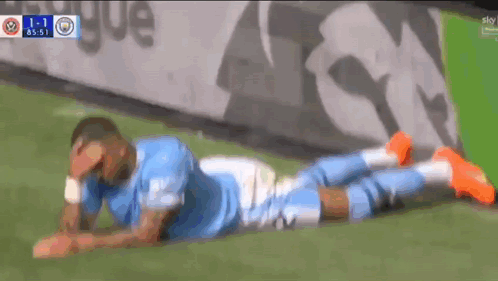 a soccer player laying on the ground with his head in his hands