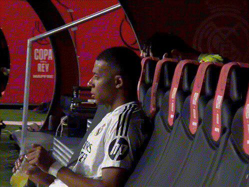 A Soccer Player Sits In A Dugout With A Sign That Says Copa Rey In The Background GIF