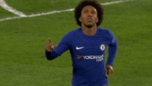 A Soccer Player Wearing A Blue Yokohama Jersey Points Upwards GIF