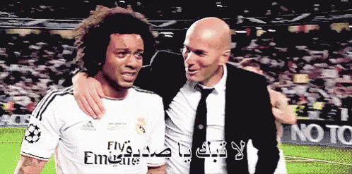 A Soccer Player Wearing A Fly Emirates Jersey Is Hugging His Coach GIF