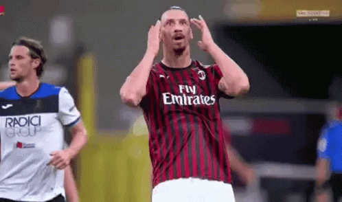 a soccer player wearing a fly emirates jersey is making a funny face