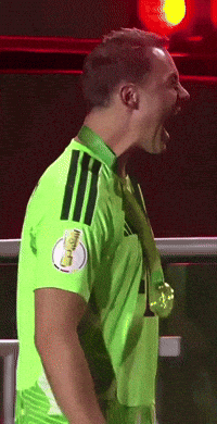 a soccer player wearing a green jersey with a gold medal around his neck