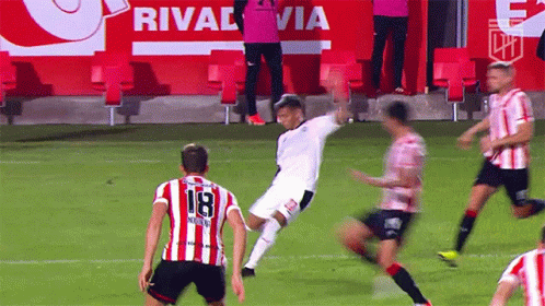 a soccer player wearing a number 18 jersey kicks the ball