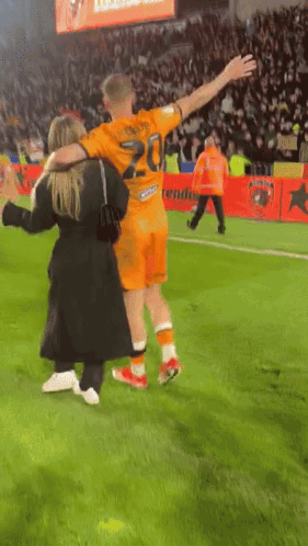 A Soccer Player Wearing A Number 20 Jersey Is Hugging A Woman GIF