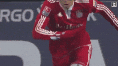 a soccer player wearing a red adidas jersey is running on the field