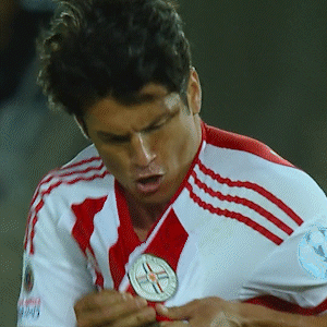 a soccer player wearing a red and white jersey is holding a medal