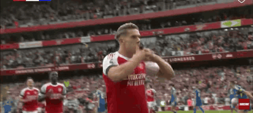 A Soccer Player Wearing A Red Emirates Fly Better Jersey Is Standing On The Field . GIF