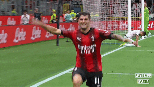a soccer player wearing a red emirates jersey celebrates