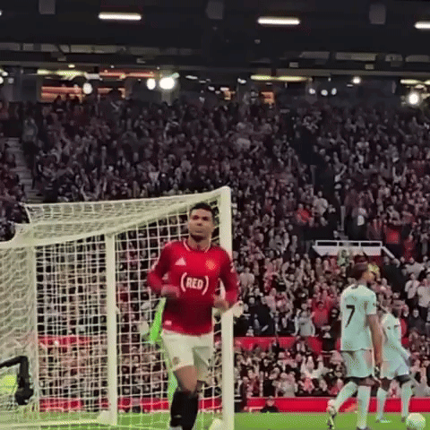 a soccer player wearing a red jersey is running towards a goal