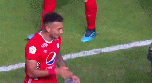 A Soccer Player Wearing A Red Pepsi Shirt Is Holding A Bottle Of Water In His Hand . GIF