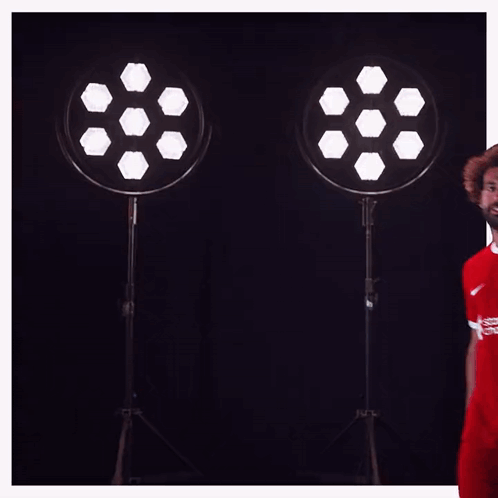 a soccer player wearing a red shirt that says standard chartered on it