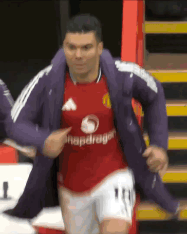a soccer player wearing a red snapdragon jersey is being helped by another player