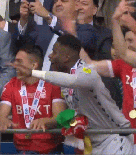 A Soccer Player Wearing A Sky Sports Shirt Stands In The Crowd GIF