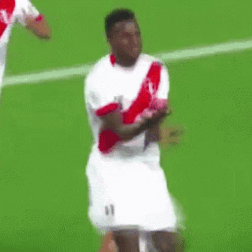 A Soccer Player Wearing A White And Red Jersey Is Dancing On The Field . GIF