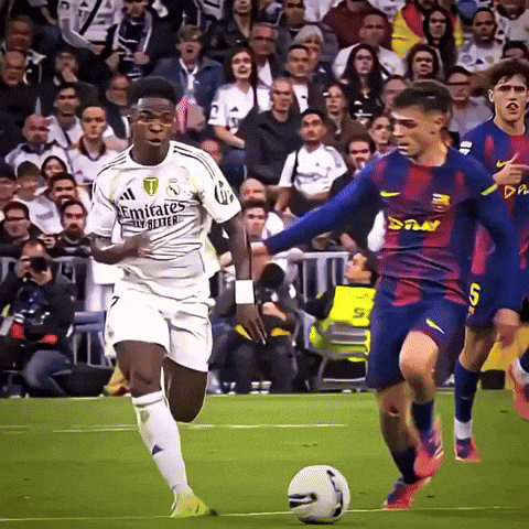a soccer player wearing a white emirates jersey is dribbling a ball