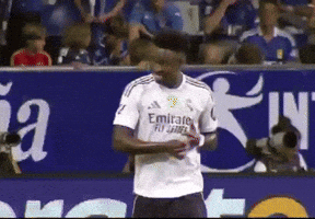 a soccer player wearing a white emirates jersey stands on the field