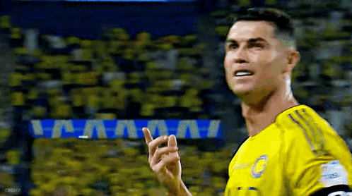 A Soccer Player Wearing A Yellow Jersey Is Pointing Up At The Crowd . GIF