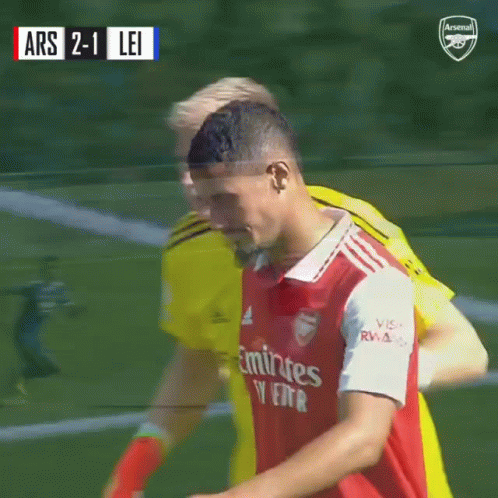 A Soccer Player Wearing An Emirates Jersey Is Hugging Another Player On The Field GIF