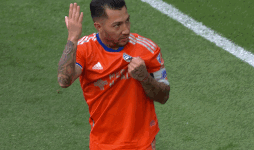 A Soccer Player Wearing An Orange Adidas Shirt Is Waving GIF