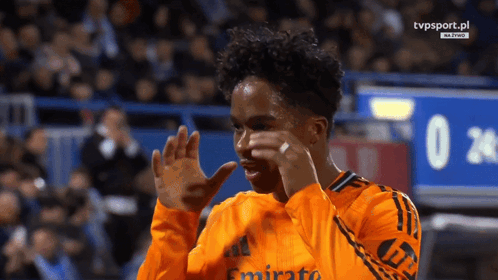 a soccer player wearing an orange jersey with emirates on it