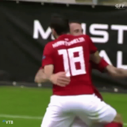 A Soccer Player Wearing The Number 18 Jersey Is Hugging Another Player GIF