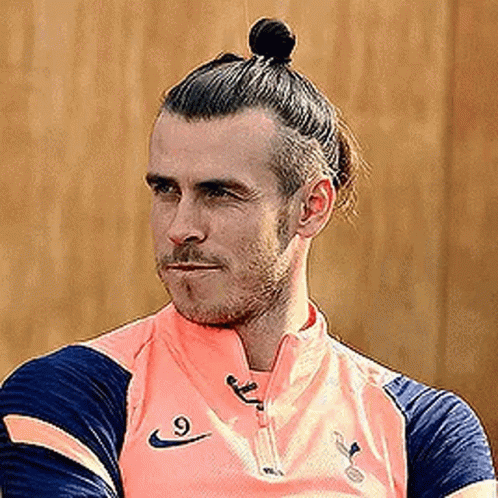 A Soccer Player With A Bun On His Head Is Wearing A Pink Shirt . GIF