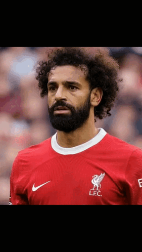 A Soccer Player With Curly Hair And A Beard Is Wearing A Red Shirt . GIF