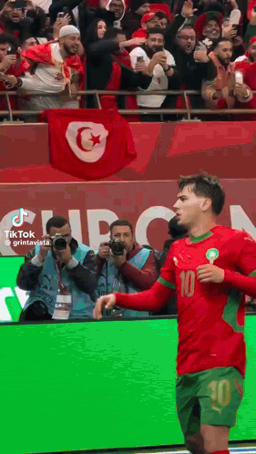 a soccer player with the number 10 on his jersey stands in front of a crowd