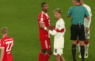 a soccer player with the number 26 on his shorts is kissing another player on the cheek