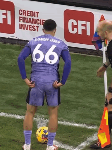 a soccer player with the number 66 on his jersey stands on the field