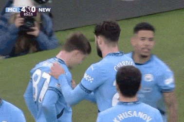 a soccer player with the number 87 on his jersey hugs another player