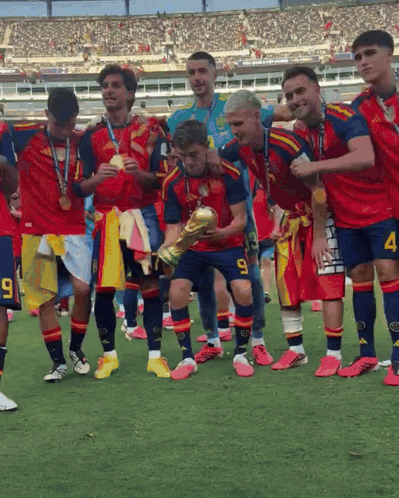 a soccer player with the number 9 on his shorts is holding a trophy with his teammates