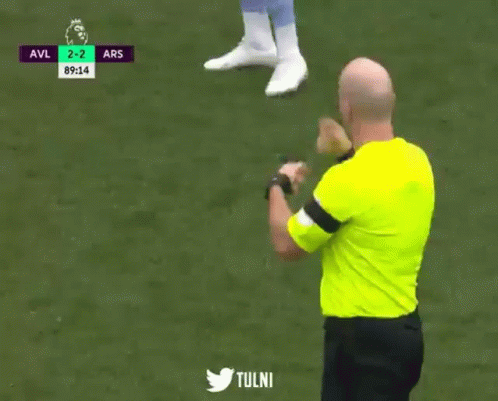 A Soccer Referee Wearing A Yellow Shirt Is Pointing At A Player During A Game GIF