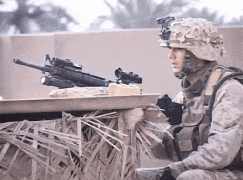 A Soldier In A Helmet Holds A Gun In His Right Hand GIF